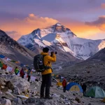 Traveler at Everest Base Camp Trek celebrating sunset with mountains in background.